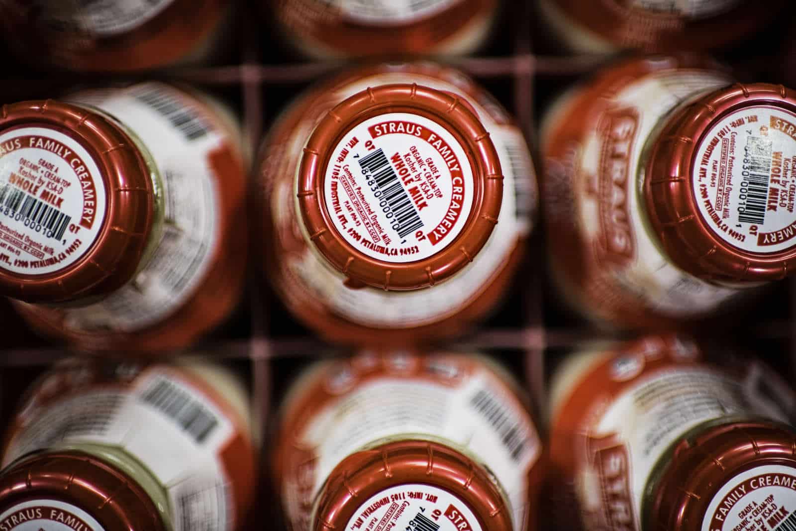 A top-down view of Straus Family Creamery's organic whole milk in glass bottles with shiny red lids.